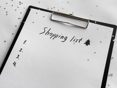 Festive shopping list on clipboard with holiday decorations and stars photo