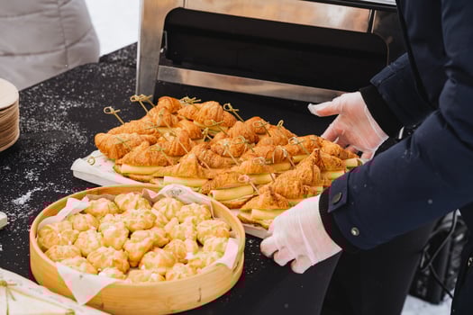 Hands lay out food on the table, cheese sandwiches, off-site catering on the street, treats, sweet buns. photo