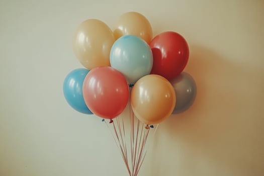 Colorful balloons resting against a white wall on a bright sunny day in an urban area photo