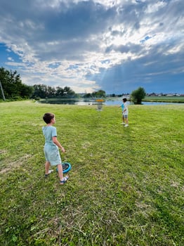 Children playing frisbee golf outdoors on a sunny day near the lake photo