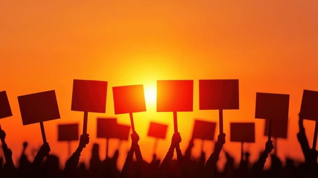 Silhouetted hands holding protest signs against a vibrant sunset backdrop. photo