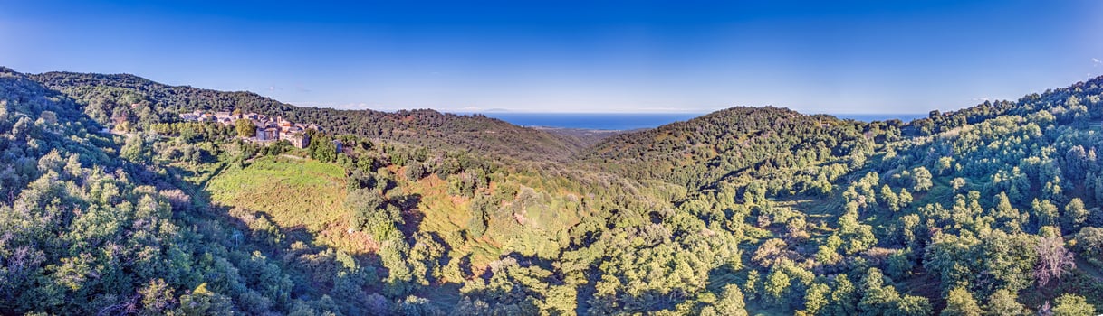Aerial panorama of a traditional Corsican mountain village with views of the dramatic eastern coastline photo