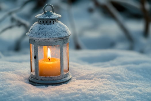 A lantern casting warm light on fresh snow in a quiet winter setting photo