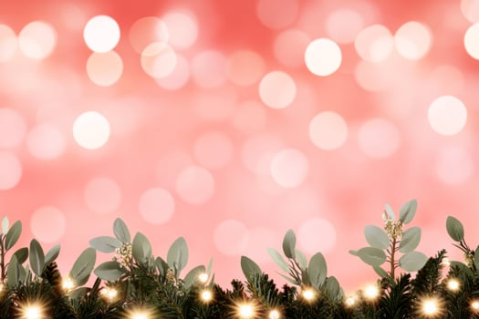 Warm glowing Christmas lights illuminate festive evergreen branches against a soft red background photo