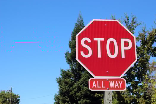 Road sign STOP close-up against blue sky and green leaves. Photo on a sunny day