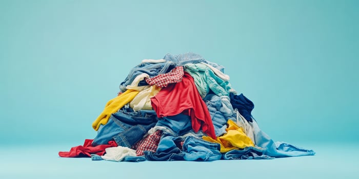 A vibrant heap of freshly laundered clothing items has been artfully displayed, showcasing a delightful variety of textiles that beautifully contrast against a simple and calming blue backdrop photo