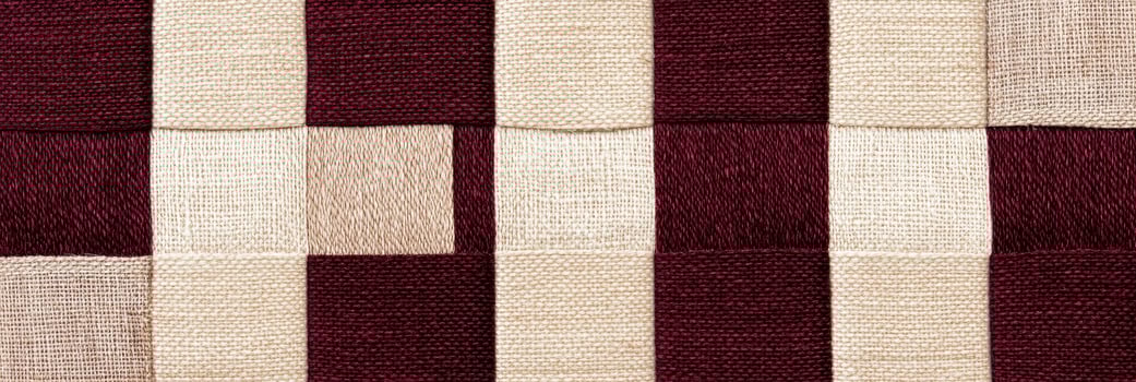 Elegant close-up of rich burgundy and beige fabric texture with warm lighting highlights detail and softness photo