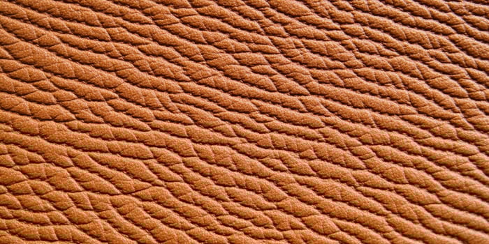Close-up view of rich brown leather texture highlighting intricate details and warm lighting effects photo