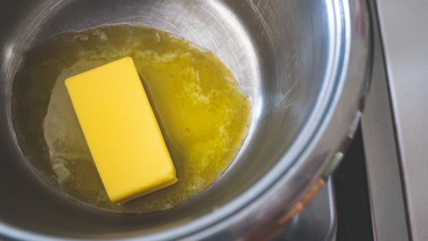 A stick of butter melting in a pot cooking close up photo