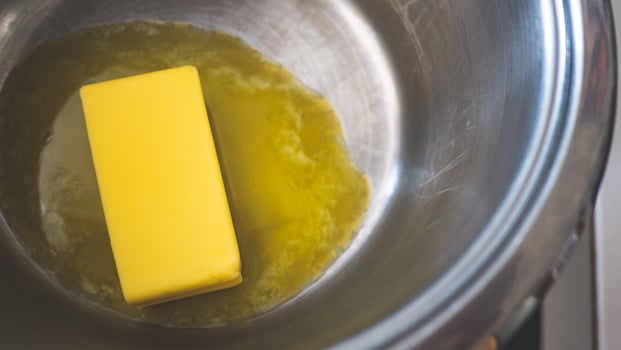 A stick of butter melting in a pot cooking close up photo