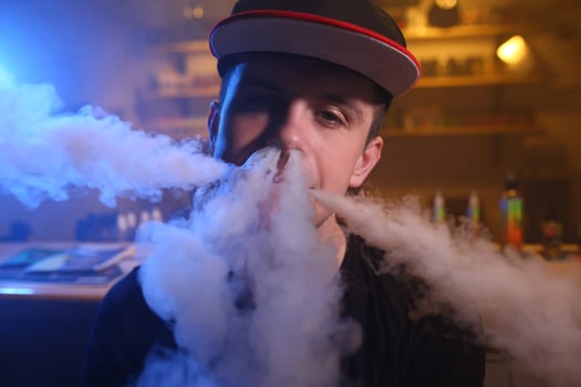 Vaping man in a cloud of vapor in a vape bar. close-up. photo