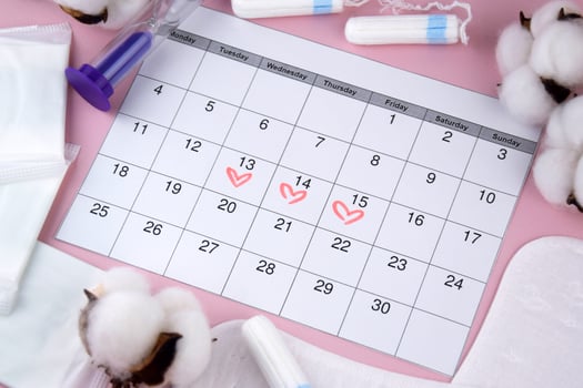 Women's menstrual pads, tampons, female menstruation calendar and alarm clock on a pink background. photo