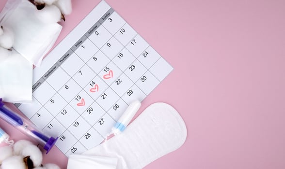 Women's menstrual pads, tampons, female menstruation calendar and alarm clock on a pink background. photo