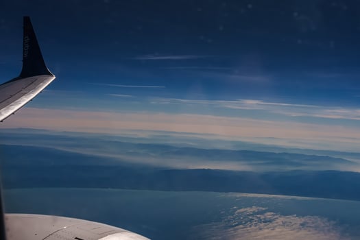 Aerial view from airplane window above green ground. View from the airplane window with beautiful clouds at sunrise. Earth and sky as seen through window of an airplane. photo