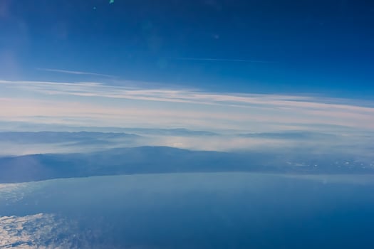 Aerial view from airplane window above green ground. View from the airplane window with beautiful clouds at sunrise. Earth and sky as seen through window of an airplane. photo