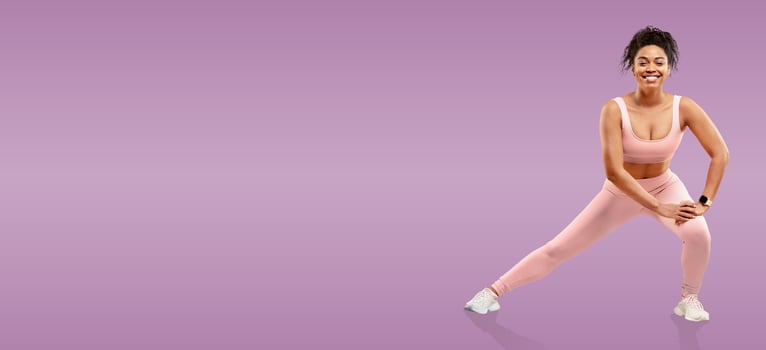 A woman is stretching her leg while wearing a light pink athletic outfit. She smiles confidently, promoting fitness and wellness in a vibrant purple setting that inspires motivation. photo