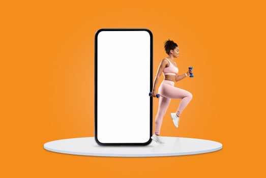 A woman wearing athletic clothing engages in an exercise routine while holding dumbbells, positioned next to a large smartphone outline on a vibrant orange background. photo