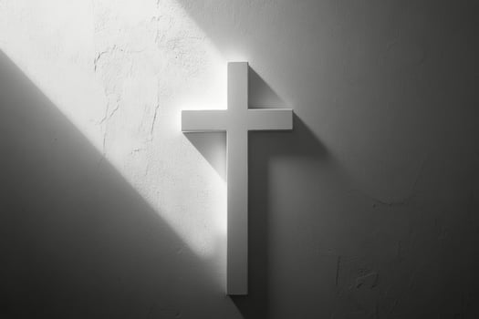 A white cross casting shadows on a textured wall in soft light during the early morning hours photo