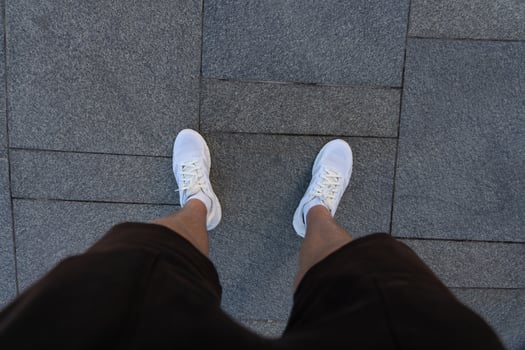 A guy in black shorts and white sneakers, standing on a granite tile photo