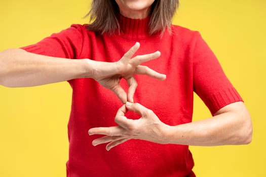 Portrait of senior woman wearing stylish red sweater, gesturing, showing symbols with fingers photo