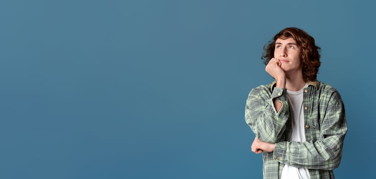 Charming teenage guy deep in thought on turquoise background photo