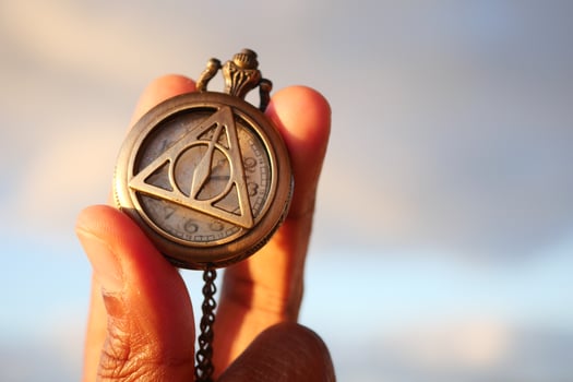 A Hand Holding an Intricate and Detailed Pocket Watch Beneath a Beautiful Scenic Sky photo