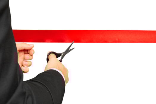 Scissors are cutting red ribbon or tape. Isolated on white background. photo