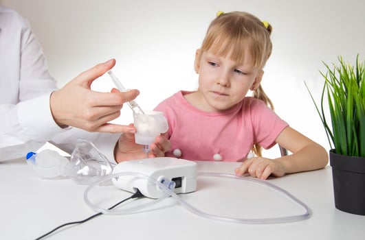 A doctor is putting a drug into a nebulizer for the treatment of respiratory diseases in a little girl 5 years old. Inhalation for the treatment of bronchitis and pneumonia photo