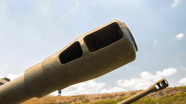 The green muzzle of a tank against the blue sky. The concept of military conflicts and children, war. Copy space for text photo