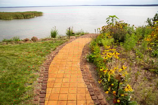 Tile path in the country house around lawns and flower beds which leads to the lake. Landscape design, background photo