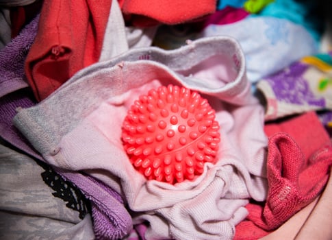 Red ball for washing clothes in the washing machine. Improving the quality of washing, close-up photo