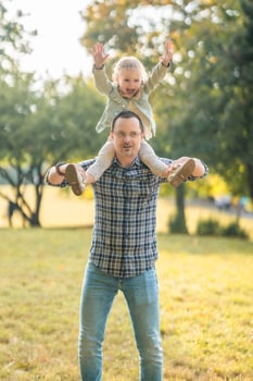 Young father and cute little daughter having fun together in autumn park at sunset light of Prague, Europe. High quality photo