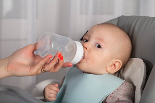 A mother feeds a baby with a milk formula with bifidobacteria from a bottle. Feeding children. photo