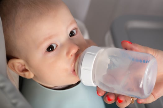 A mother feeds a baby with a milk formula with bifidobacteria from a bottle. Feeding children. photo