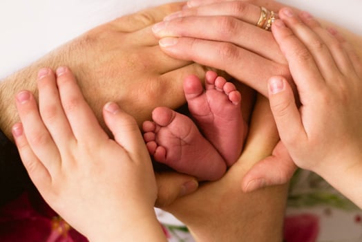 A family holding hands with a baby's feet photo
