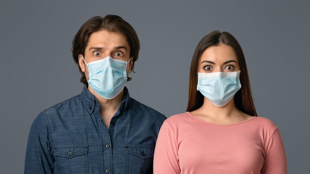 Virus Outbreak Danger. Portrait Of Scared Man And Woman In Protective Face Masks, Looking At Camera With Frightened Face Expression, Light Background photo