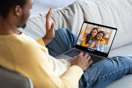 Two friends share a heartfelt moment during a call on a laptop while sitting on a comfy couch, conveying warmth and connection in a relaxed indoor setting. photo