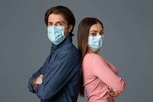 Confident Young Man And Woman In Protective Medical Masks Standing Back To Back With Folded Arms Over Light Background photo