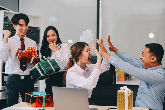 full length view of a group of business team wearing red Santa hat and exchange gift box together in the office for Christmas. photo