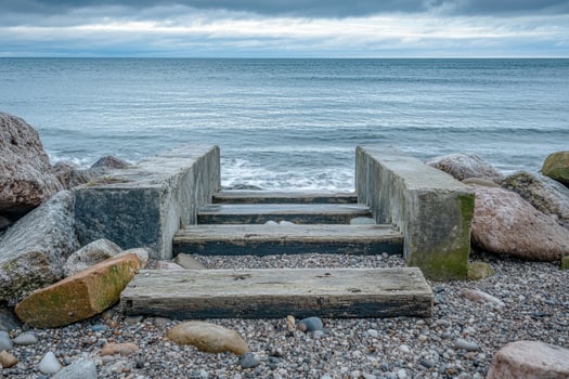 Wooden steps leading to the sea with rocky shore and stormy clouds. photo