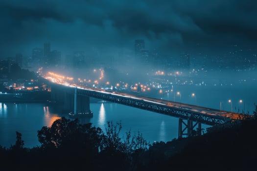 A bridge illuminated at night with a city skyline in the background. photo