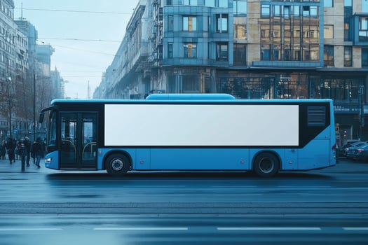 Blue bus with empty billboard driving on city street photo