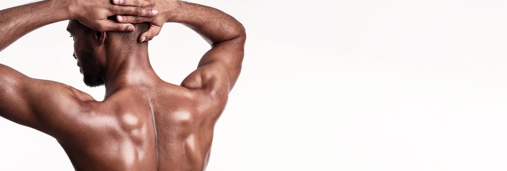 Building Muscle. Fit Bodybuilder Guy Posing Standing Back To Camera Over White Background. Studio Shot, Panorama photo
