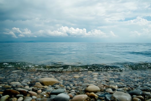 Calm blue water laps against a pebble beach. photo