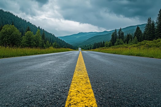 Empty asphalt road leading through a mountain valley with a yellow dividing line. photo