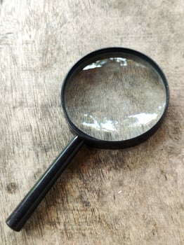 magnifying glass isolated on wood background. magnifier tool. photo