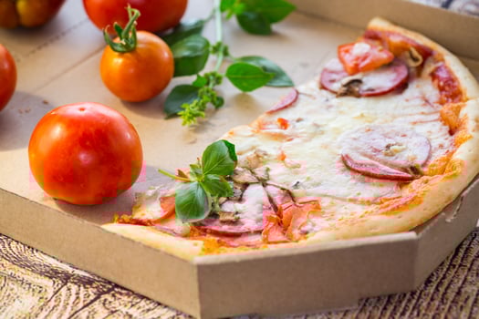 cooked pizza with salami and sausage in a box on a wooden table photo