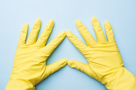 Home cleaning concept. Hands in yellow gloves for cleaning on blue background. photo