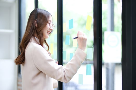 Businesswoman writing on sticky notes while planning business strategy photo