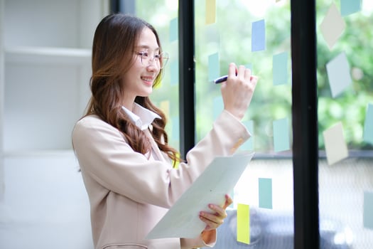 Businesswoman writing on sticky notes while planning business strategy photo